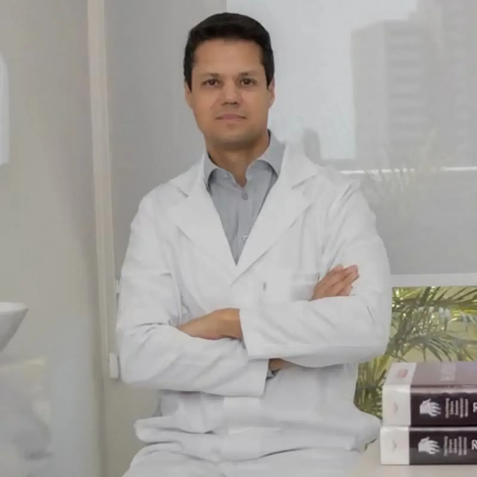 Dr. Odilon De Bortoli de jaleco e braços cruzados no consultório